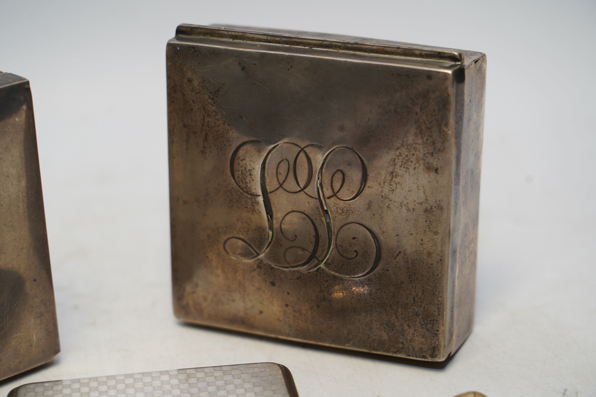 Two early 20th century silver mounted square cigarette boxes, largest 10.1cm, a similar silver cigarette case and three other silver items. Condition - fair to poor